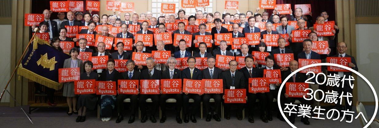 定期総会・懇親会の集合写真。校友が龍谷の手旗を掲げている